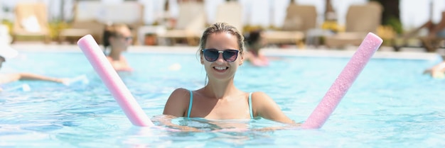 Uma mulher está envolvida em aqua fitness em uma piscina ao ar livre, aeróbica embaçada, azul claro