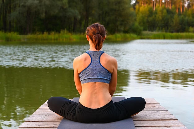 Uma mulher está envolvida em exercícios de fisioterapia no lago na natureza. o conceito de tratar doenças com a ajuda do exercício.