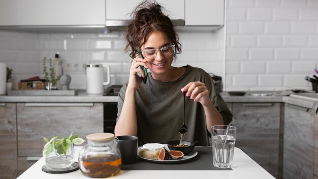 Uma mulher está falando ao telefone enquanto toma café da manhã.