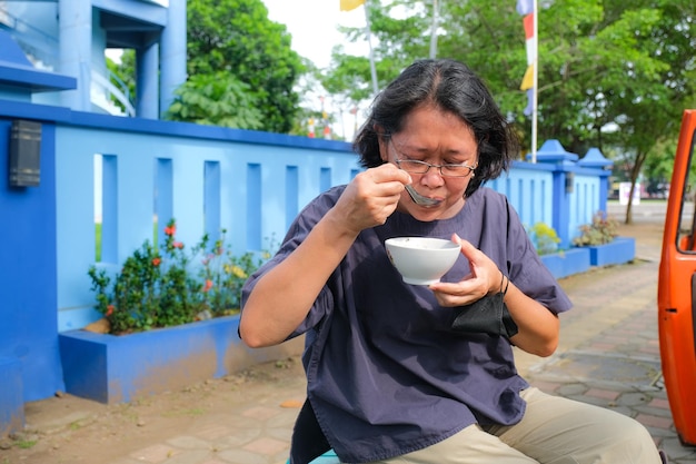 Uma mulher está fazendo uma pausa e saboreando uma tigela de sobremesa tradicional javanesa