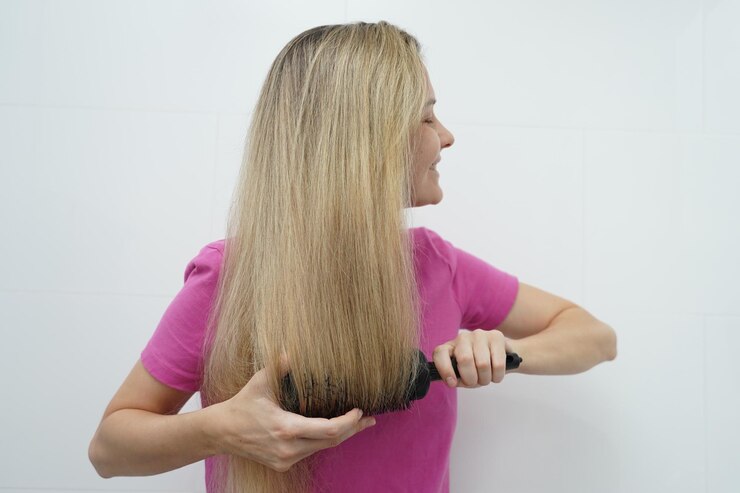 Foto uma mulher está habilmente penteando seu cabelo usando um secador e uma escova enquanto está no banheiro