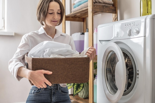 Uma mulher está lavando roupas brancas em uma máquina de lavar em uma lavandaria