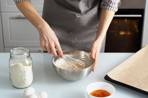 Uma mulher está na cozinha assando bagels com geleia. pastelaria doce com suas próprias mãos. mulher amassar massa para assar.