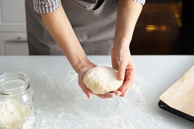 Uma mulher está na cozinha assando bagels com geleia. Pastelaria doce com suas próprias mãos. Mulher amassar massa para assar.