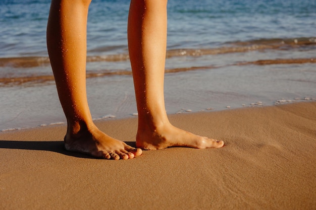 Uma mulher está na praia em frente ao oceano.