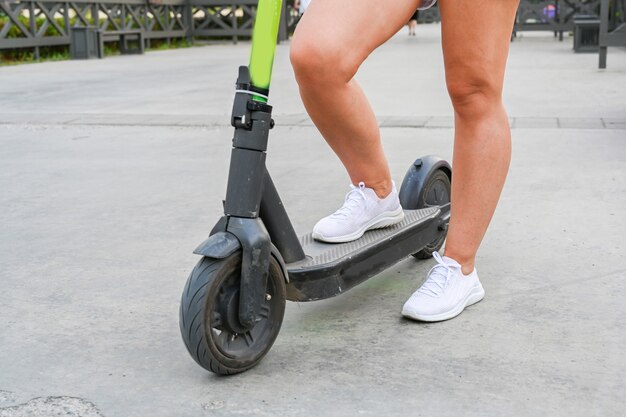 Uma mulher está parada com uma scooter na margem de Kazan. Transporte ecológico.