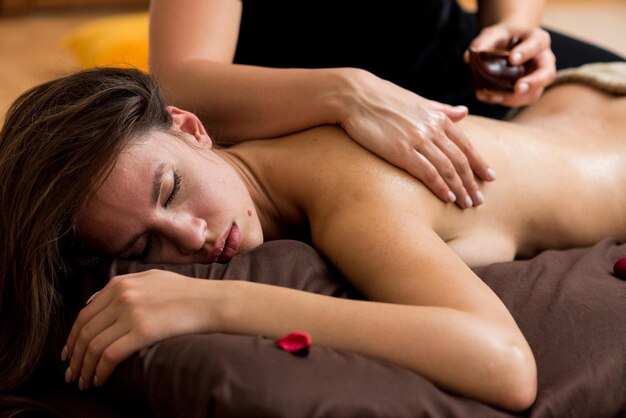 Foto uma mulher está recebendo uma massagem com uma flor vermelha no braço.