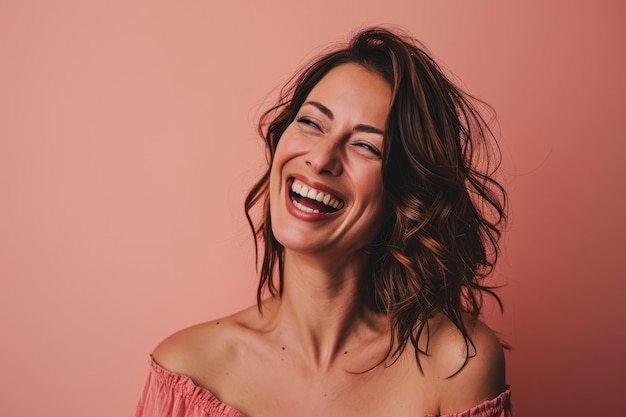 Uma mulher está rindo e sorrindo na frente de um fundo rosa