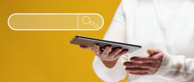 Uma mulher está segurando um tablet eletrônico em um fundo amarelo Pesquisar informações na Internet acesso gratuito à rede