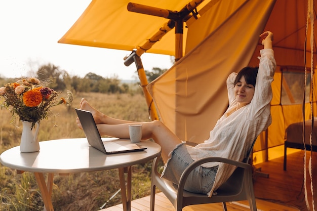 Foto uma mulher está sentada em uma cadeira com um laptop e uma xícara de café