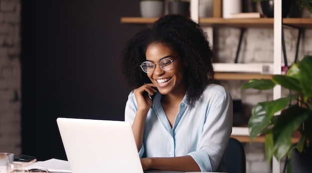 Uma mulher está sentada em uma mesa com um laptop e sorri para a câmera.