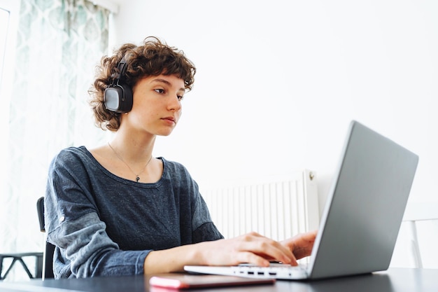 Uma mulher está sentada em uma mesa com um laptop e um fone de ouvido na cabeça.