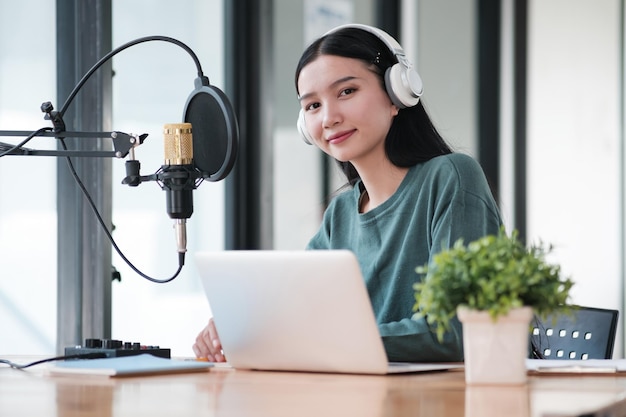 Uma mulher está sentada em uma mesa com um laptop e um microfone
