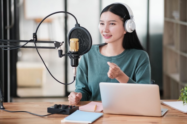 Uma mulher está sentada em uma mesa com um microfone e um laptop