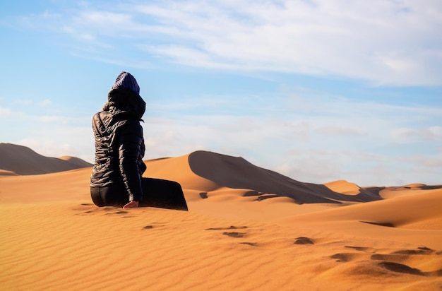 Uma mulher está sentada na duna de areia dourada do deserto do namibe. áfrica