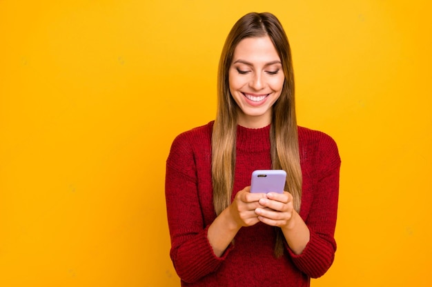 Foto uma mulher está sorrindo e segurando um telefone com um fundo amarelo