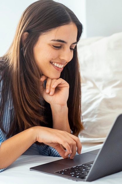 uma mulher está usando um laptop com um sorriso no rosto