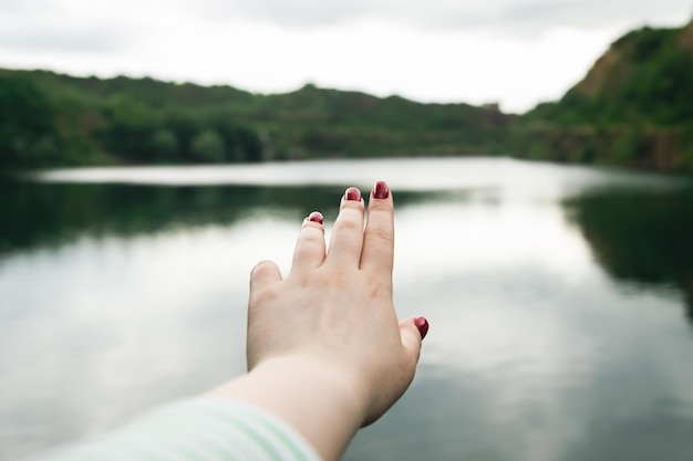 Uma mulher estende a mão para a natureza o fundo do rio o conceito de cuidar da natureza