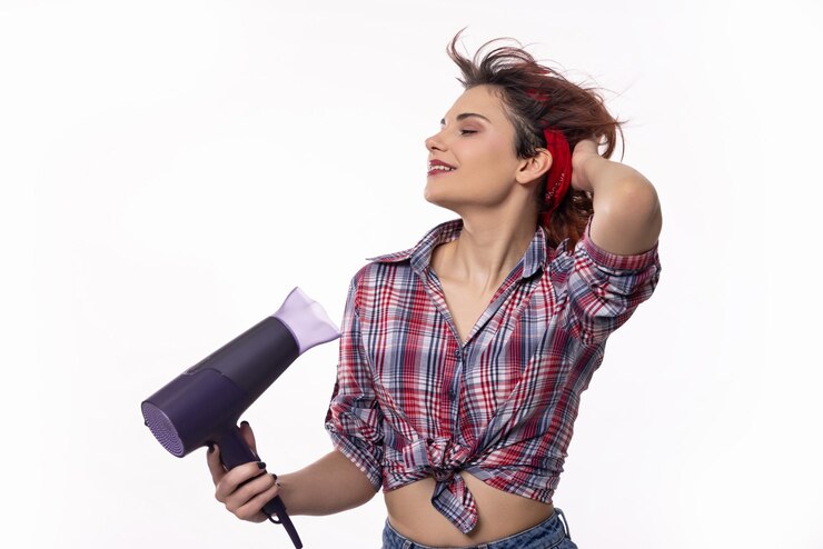 Foto uma mulher estilizada com um secador de cabelo durante uma sessão de fotos à moda ao ar livre