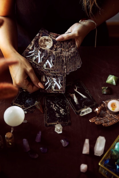 Foto uma mulher extrai uma carta de oráculo do baralho em seu altar de bruxa com várias pedras semipreciosas na mesa