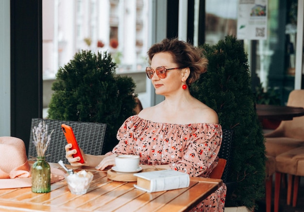 Uma mulher falando ao telefone Uma mulher com um telefone celular está sentada em um café uma mulher de vestido e um chapéu em um café