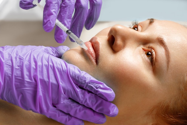 Uma mulher faz a correção da forma dos lábios em uma clínica de cosmetologia, injeções de lábios, aumento de lábios