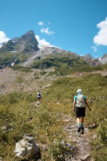 Uma mulher faz caminhadas na vista das montanhas por trás da montanha da paisagem de verão na neve e nas rochas