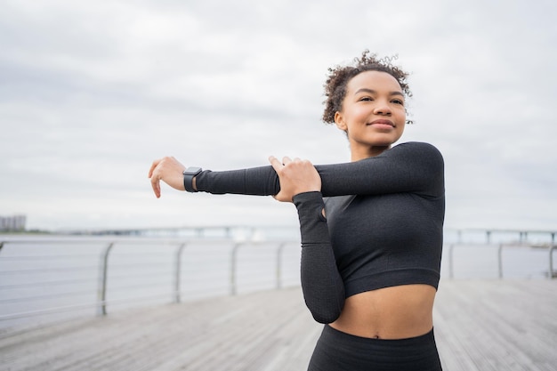 Uma mulher faz exercícios de fitness usa um rastreador na mão um relógio inteligente para treinamento esportivo em roupas esportivas