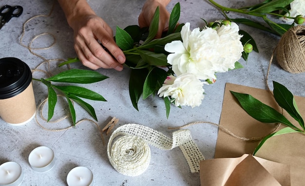 Uma mulher faz um buquê de peônias um buquê de flores de poda de papel kraft estilite faz um buquê