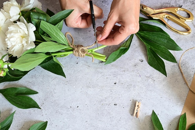 Uma mulher faz um buquê de peônias um buquê de flores de poda de papel kraft estilite faz um buquê