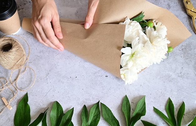 Uma mulher faz um buquê de peônias um buquê de flores de poda de papel kraft estilite faz um buquê