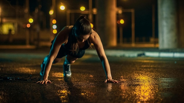 Foto uma mulher fazendo flexões em uma estrada molhada à noite.