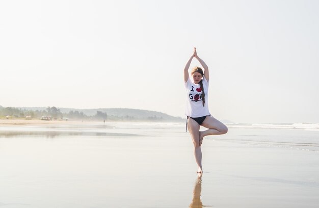 Foto uma mulher fazendo ioga em uma praia em vancouver