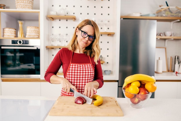 Uma mulher fazendo salada de frutas lanche saudável na cozinha em sua casa
