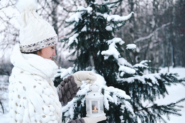 Foto uma mulher feliz com uma lanterna nas mãos em um parque de inverno com árvores cobertas de neve