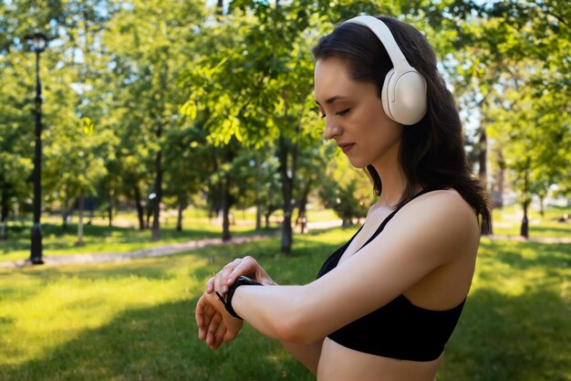uma mulher fica de pé e ouve música em fones de ouvido e bebe alegremente depois de um passeio no parque