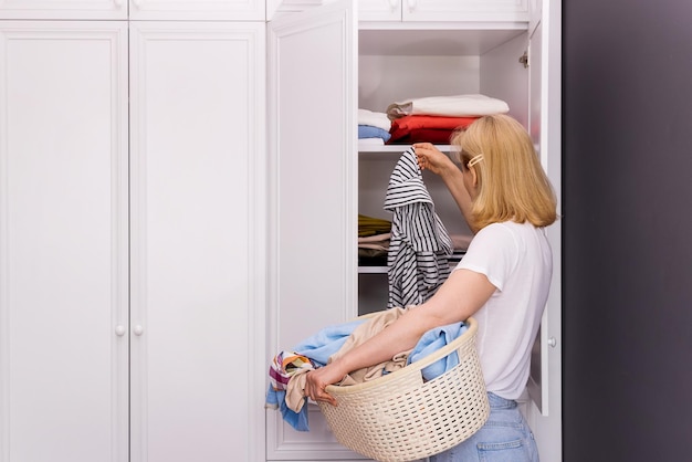 Uma mulher fica na frente de um armário branco coletando coisas para lavar