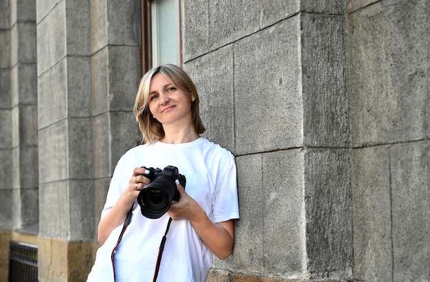 uma mulher fotógrafa com uma câmera na mão uma mulher fotógrafa com uma câmera nas mãos caminha pelas ruas da cidade e anda pelas ruas da cidade