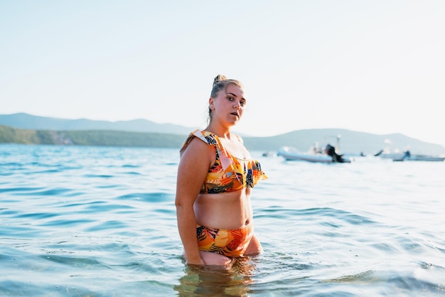 Uma mulher gorda aprecia o mar ao pôr do sol Foco seletivo