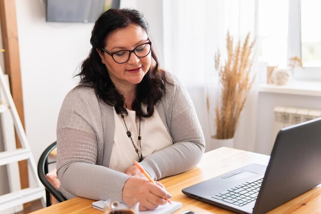 Uma mulher gorda está sentada em uma mesa com um laptop.