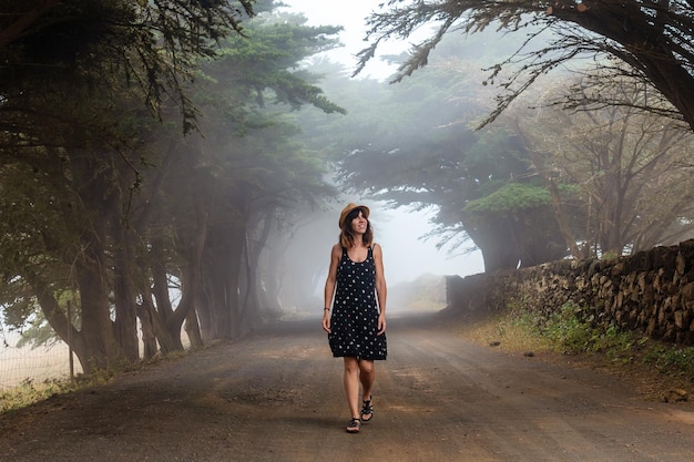 Uma mulher gosta de caminhar por árvores nebulosas em direção à floresta de zimbro em El Hierro, Ilhas Canárias