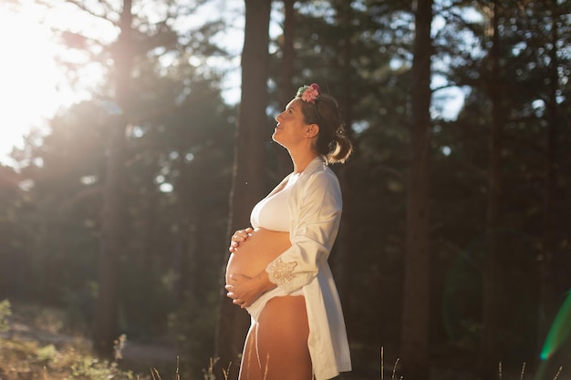 Uma mulher grávida acaricia sua barriga e seu futuro filho vestindo um roupão de seda