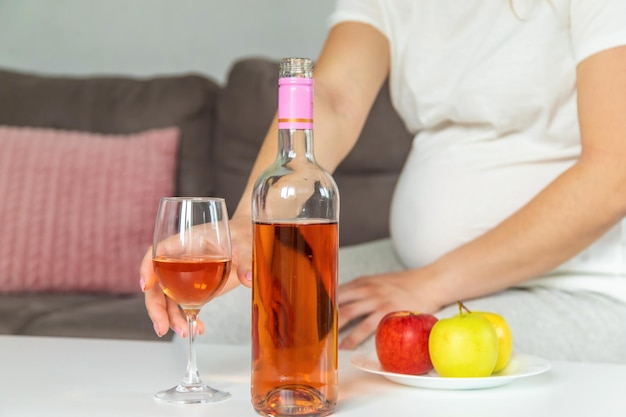 Uma mulher grávida bebe vinho em um copo Foco seletivo