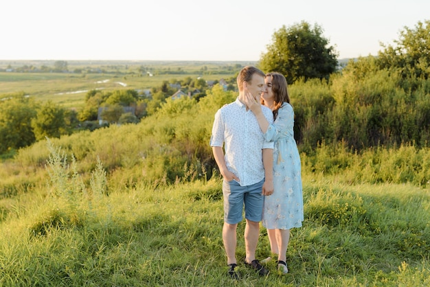 Uma mulher grávida caminha no campo com o marido