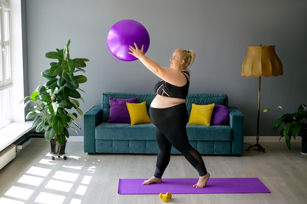 Uma mulher grávida com obesidade plussize está fazendo fitness em casa