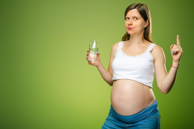 Uma mulher grávida com um copo de água deve uma mulher grávida beber muita água ou não