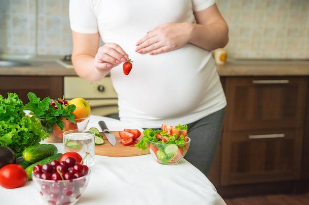 Uma mulher grávida come legumes e frutas