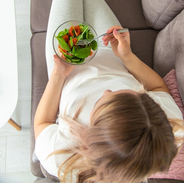 Uma mulher grávida come uma salada com legumes Foco seletivo