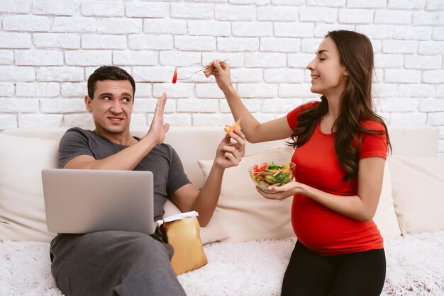 Uma mulher grávida dá uma salada para um homem.