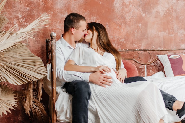 uma mulher grávida está deitada na cama com o marido